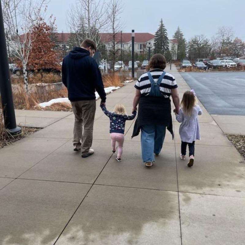 Jason, his wife, and two kids walking hand in hand. 