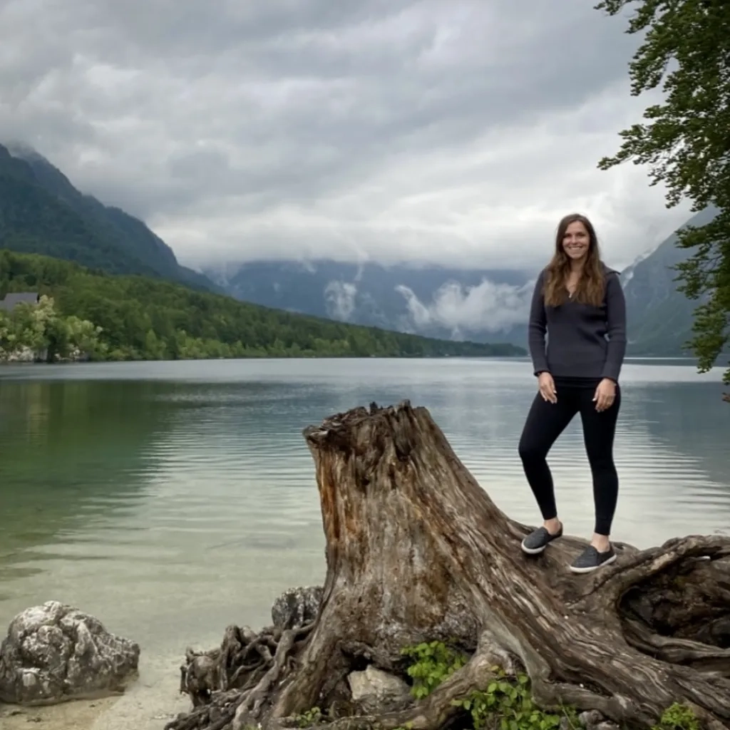 Hillary standing on a tree stump in nature.