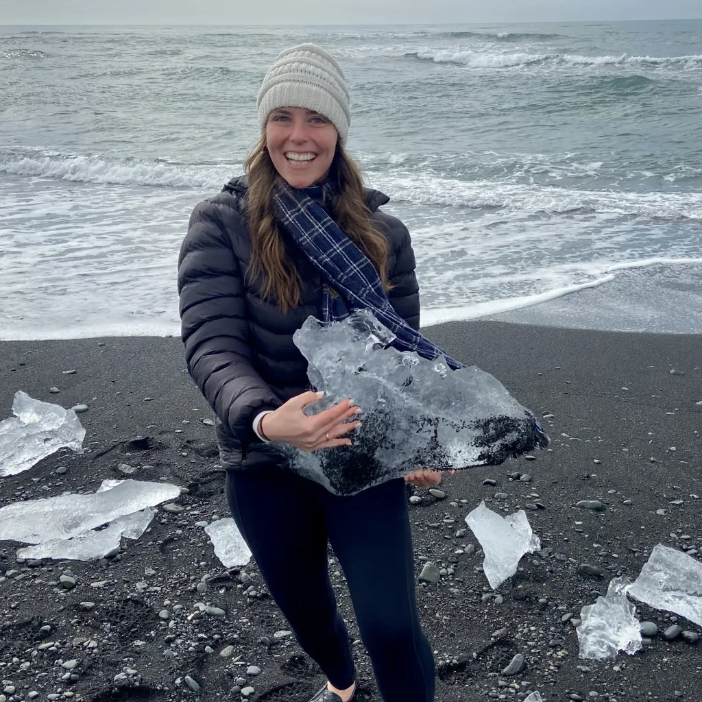Hillary holding a chunk of ice next to the ocean.